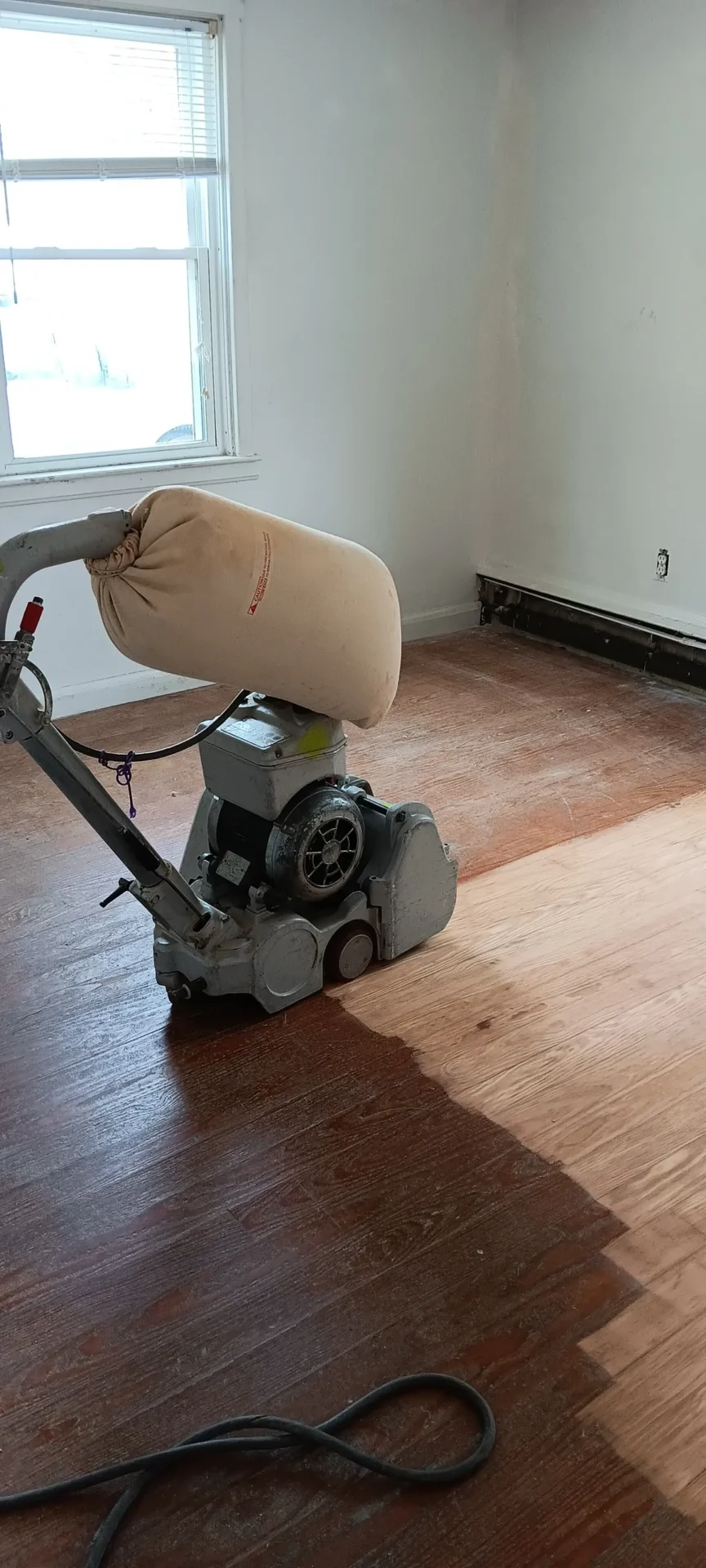A floor sander is on the ground in a room.