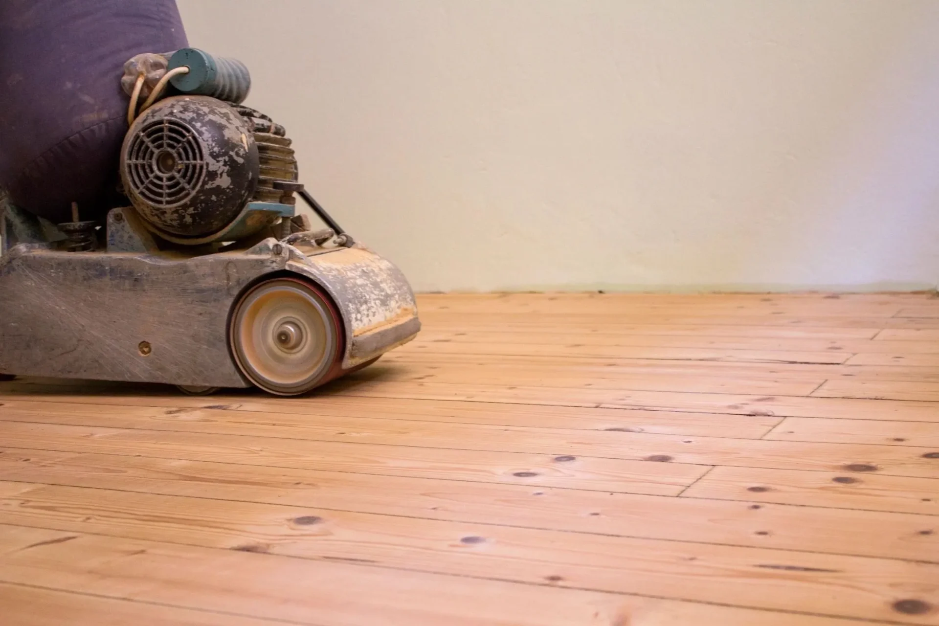 A person using an electric mower on the floor.