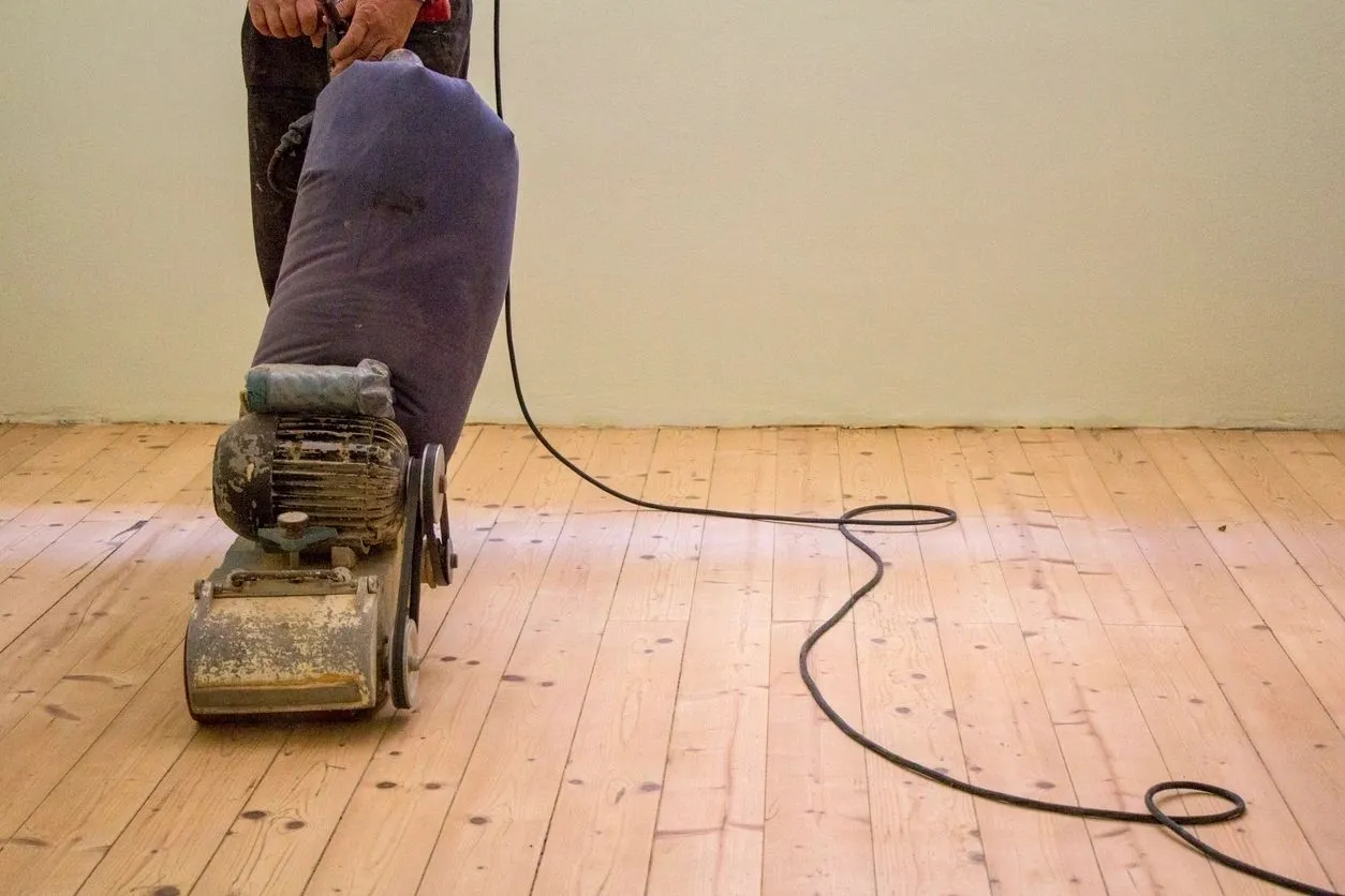 A person is using a vacuum on the floor.