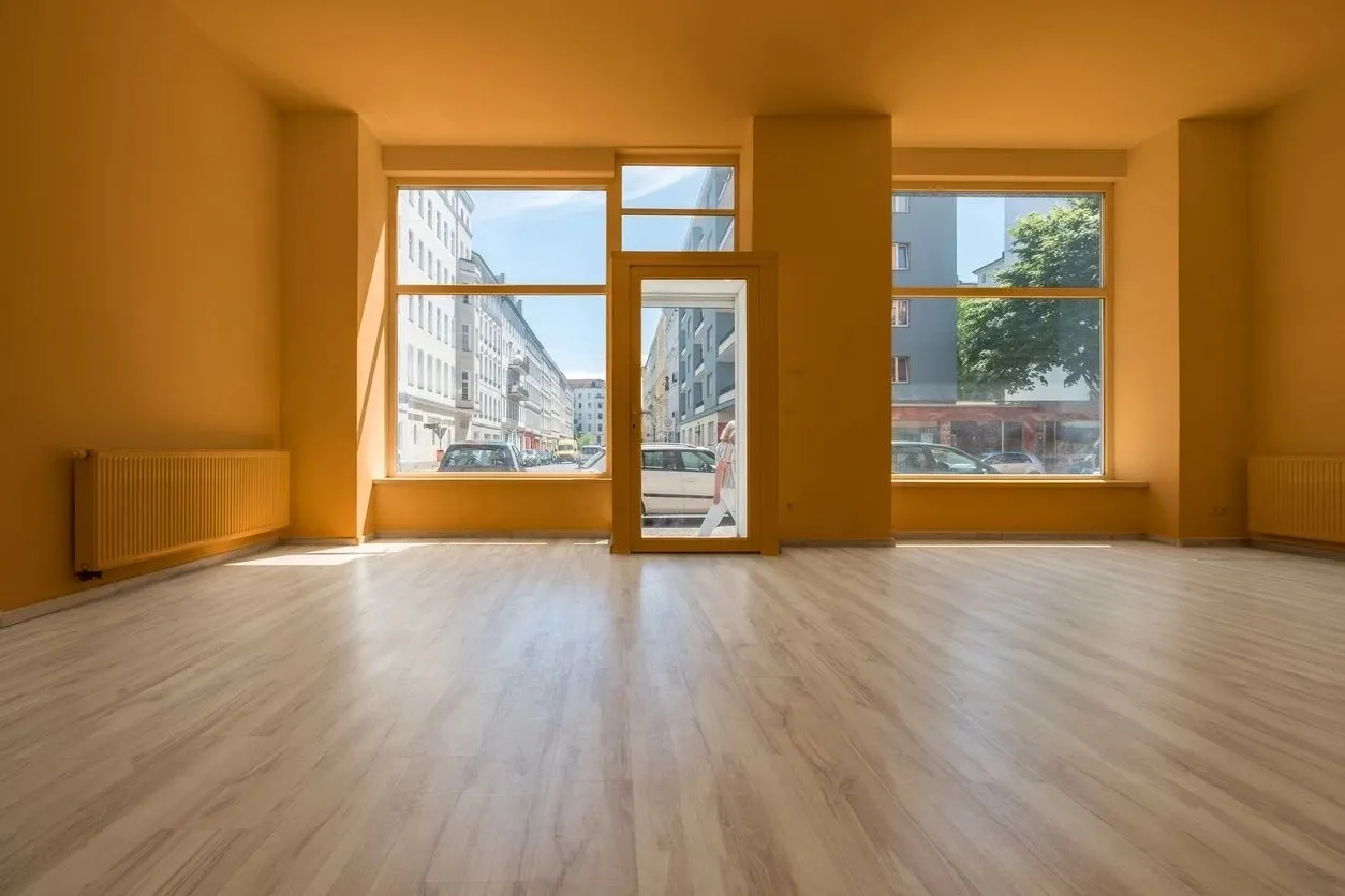 A large empty room with two windows and wooden floors.
